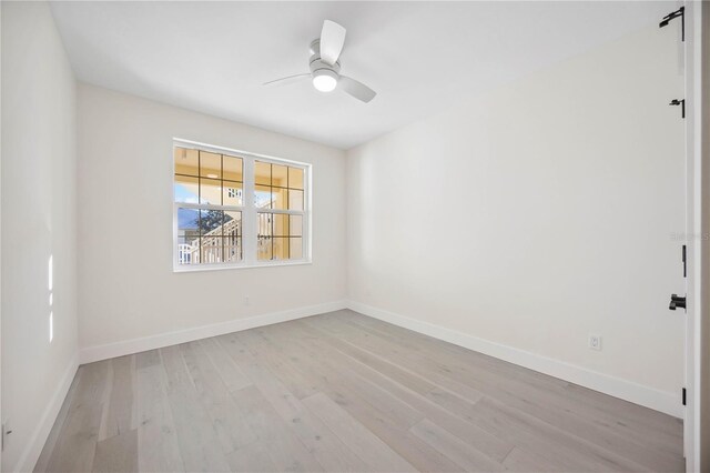 spare room with light wood-type flooring, baseboards, and ceiling fan