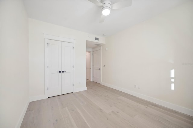 unfurnished bedroom with light wood-style flooring, a ceiling fan, baseboards, and a closet