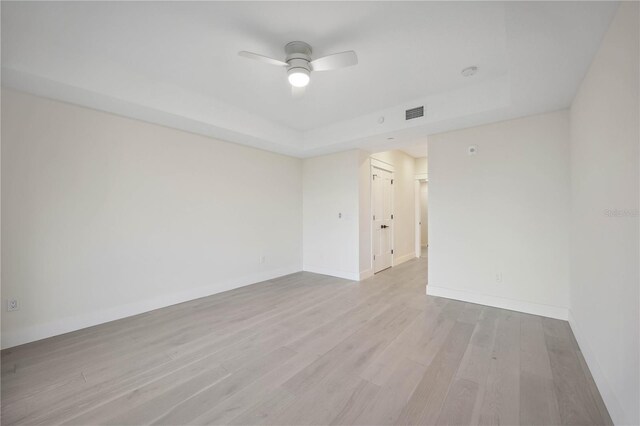 empty room featuring visible vents, a ceiling fan, baseboards, and wood finished floors