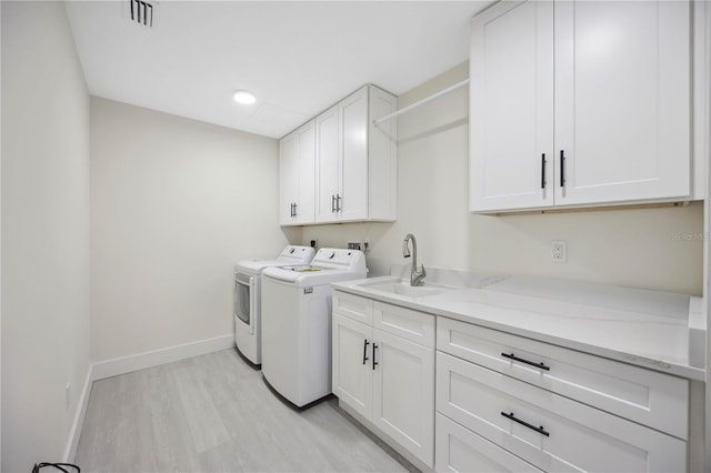 laundry area with visible vents, washer and clothes dryer, a sink, cabinet space, and baseboards