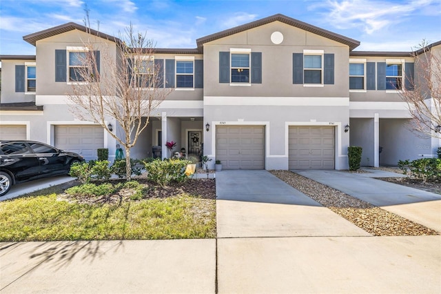 multi unit property featuring an attached garage, driveway, and stucco siding