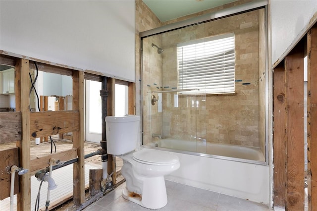 full bathroom featuring tile patterned floors, toilet, plenty of natural light, and bath / shower combo with glass door