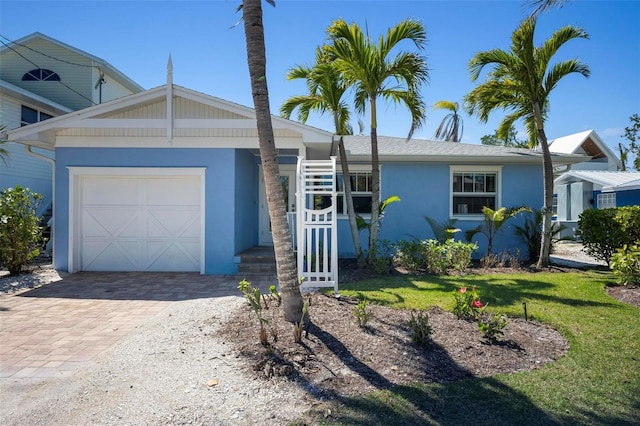 ranch-style home featuring decorative driveway, an attached garage, and stucco siding