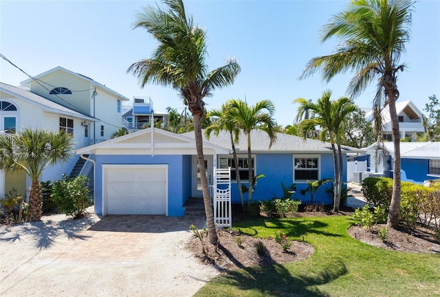 view of front of property with a front yard, decorative driveway, a garage, and stucco siding