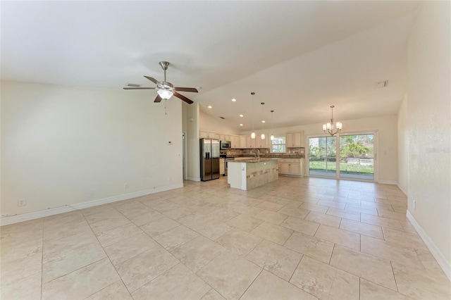 kitchen featuring an island with sink, lofted ceiling, appliances with stainless steel finishes, open floor plan, and a sink