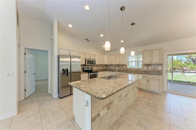 kitchen featuring stainless steel appliances, a sink, cream cabinetry, tasteful backsplash, and an island with sink