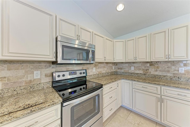 kitchen featuring light tile patterned floors, decorative backsplash, lofted ceiling, appliances with stainless steel finishes, and light stone counters