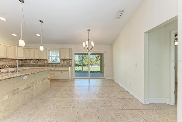 kitchen featuring tasteful backsplash, pendant lighting, a sink, and cream cabinets