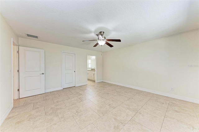 unfurnished bedroom featuring ceiling fan, connected bathroom, visible vents, and baseboards