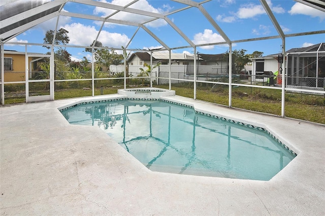 pool featuring a patio area, a residential view, glass enclosure, and an in ground hot tub