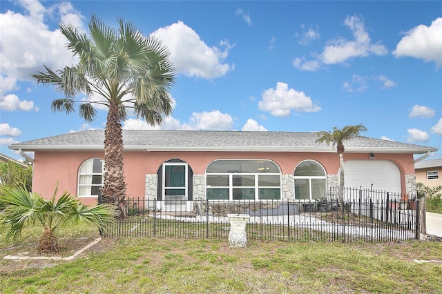 view of front of house featuring a fenced front yard, stucco siding, an attached garage, stone siding, and driveway