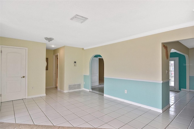 unfurnished room featuring light tile patterned floors, arched walkways, visible vents, and baseboards