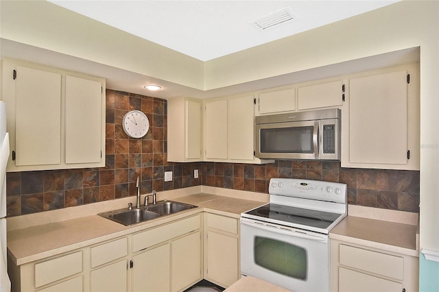 kitchen with white electric range oven, stainless steel microwave, visible vents, cream cabinets, and a sink