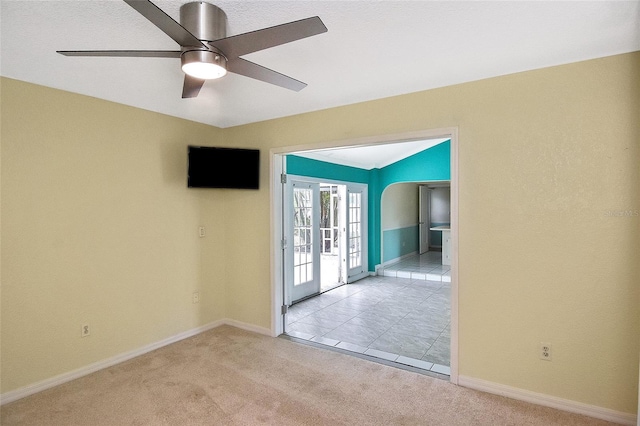 carpeted spare room featuring a ceiling fan and baseboards