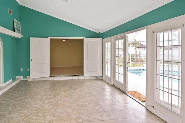 empty room featuring a wealth of natural light, lofted ceiling, visible vents, and ornamental molding