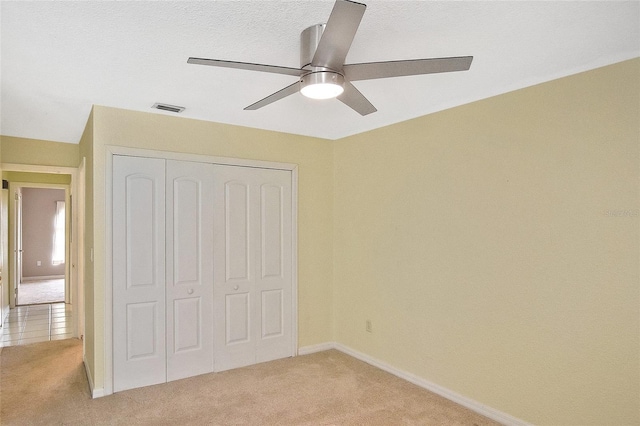 unfurnished bedroom with a closet, light carpet, visible vents, and baseboards