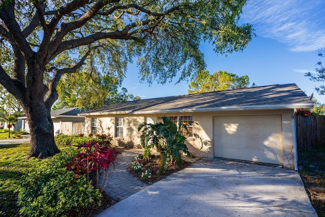 single story home featuring stucco siding, an attached garage, concrete driveway, and fence