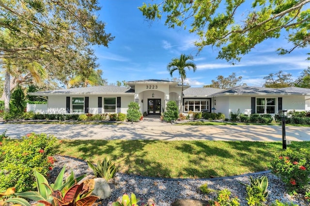 view of front of home with a front yard, french doors, and stucco siding