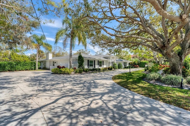 ranch-style home with driveway and a chimney