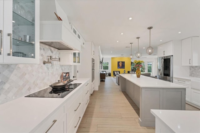 kitchen featuring black electric stovetop, light countertops, white cabinets, a kitchen island, and stainless steel fridge with ice dispenser