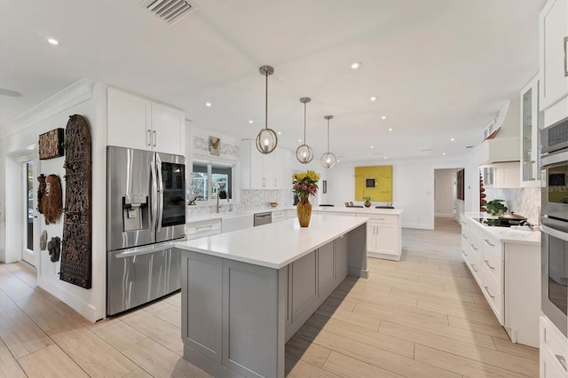 kitchen with a peninsula, visible vents, stainless steel appliances, and decorative backsplash