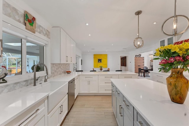 kitchen with decorative backsplash, dishwasher, decorative light fixtures, white cabinetry, and a sink