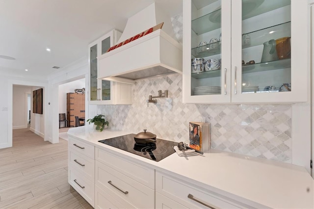 kitchen featuring tasteful backsplash, light countertops, white cabinetry, and black electric cooktop