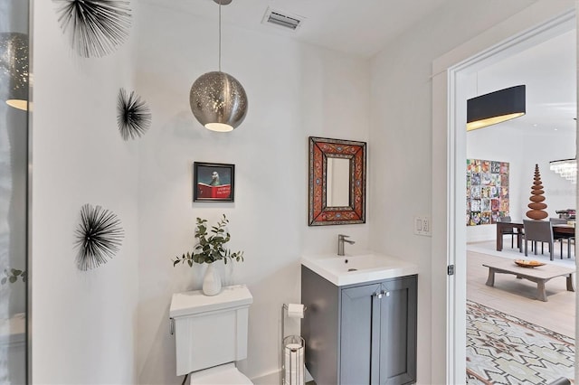 bathroom featuring toilet, vanity, and visible vents