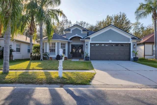 single story home with an attached garage, driveway, a front lawn, and stucco siding