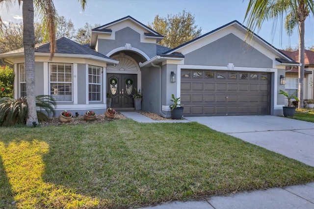 traditional-style house featuring french doors, stucco siding, a front yard, a garage, and driveway