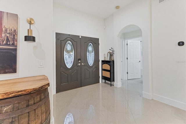 foyer with baseboards and arched walkways