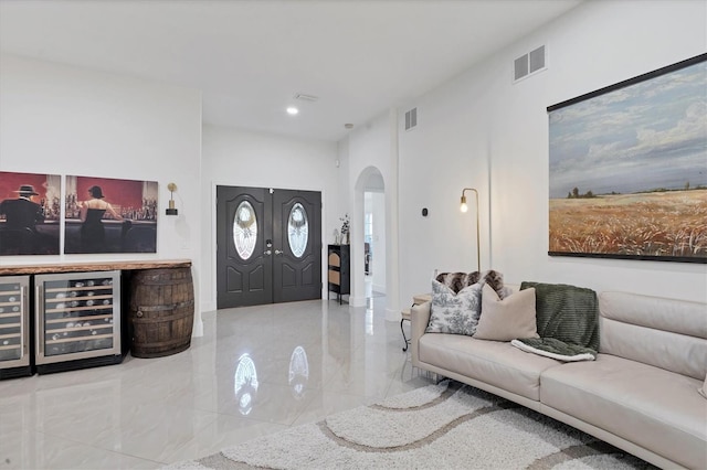 entrance foyer with arched walkways, beverage cooler, visible vents, and baseboards