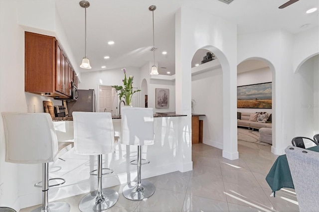 kitchen with hanging light fixtures, a breakfast bar area, brown cabinetry, and recessed lighting