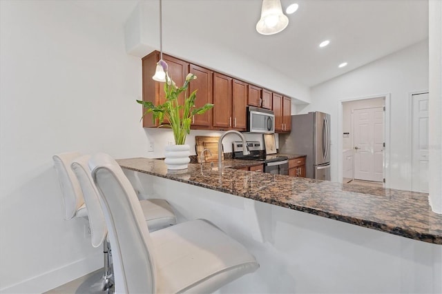 kitchen with pendant lighting, brown cabinets, stainless steel appliances, vaulted ceiling, and dark stone countertops