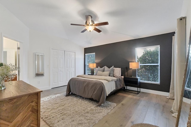 bedroom with lofted ceiling, a closet, ceiling fan, wood finished floors, and baseboards