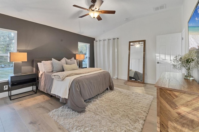 bedroom featuring light wood finished floors, lofted ceiling, visible vents, ceiling fan, and baseboards