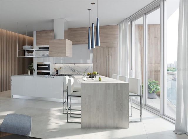 kitchen with modern cabinets, a kitchen breakfast bar, oven, a wall of windows, and wall chimney range hood