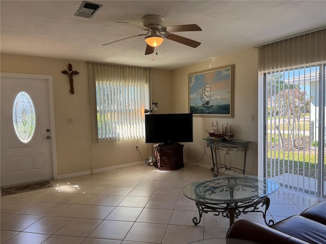 tiled foyer with ceiling fan, visible vents, and a healthy amount of sunlight