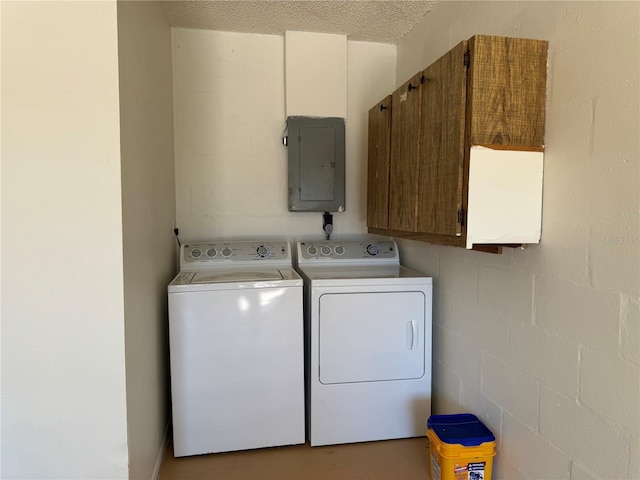 laundry area featuring concrete block wall, cabinet space, washing machine and dryer, a textured ceiling, and electric panel