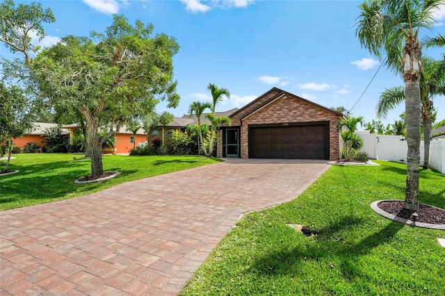 ranch-style home with an attached garage, brick siding, fence, decorative driveway, and a front yard