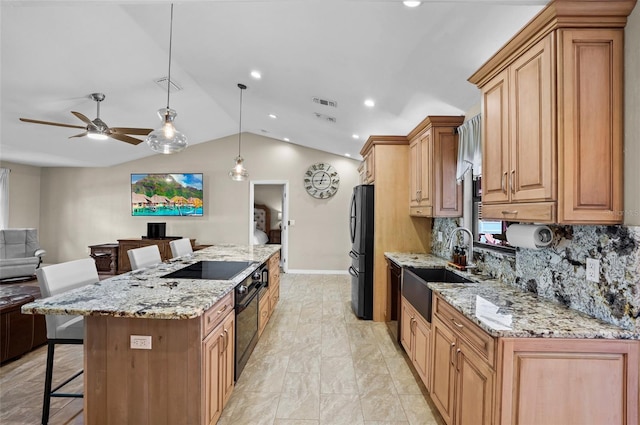 kitchen featuring a center island, a breakfast bar area, vaulted ceiling, a sink, and black appliances