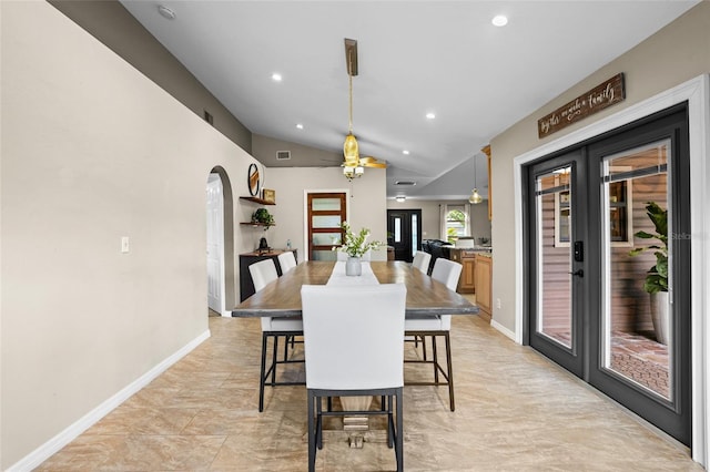 dining room featuring arched walkways, french doors, lofted ceiling, and baseboards