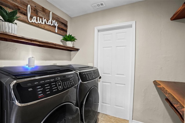 washroom with light tile patterned floors, laundry area, washing machine and clothes dryer, and visible vents