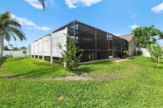 rear view of property with a lanai, a fenced backyard, and a lawn