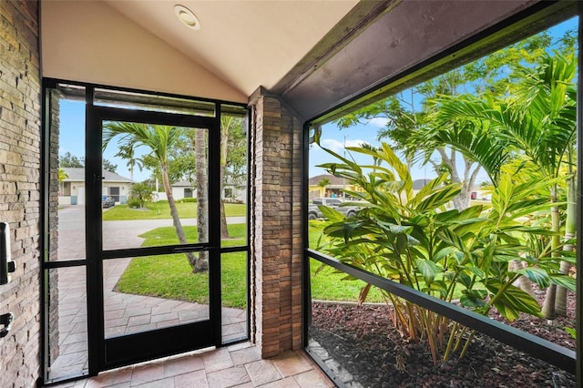 doorway to outside with lofted ceiling and stone tile floors