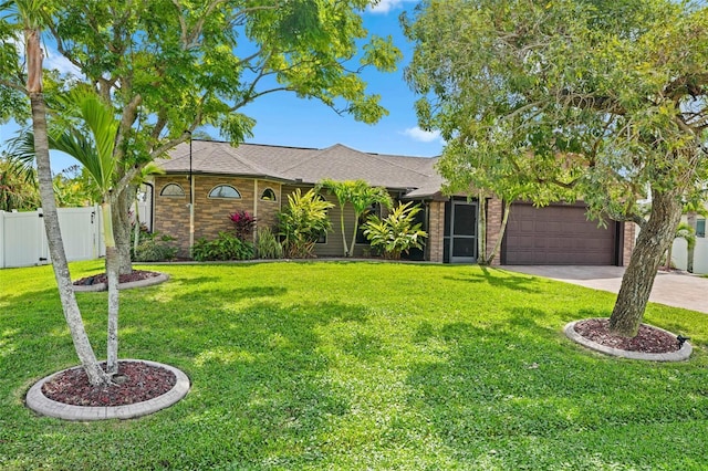 view of front of house featuring brick siding, a front yard, fence, a garage, and driveway