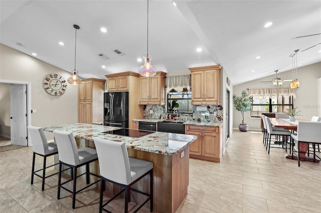 kitchen featuring a center island, vaulted ceiling, a sink, black appliances, and a kitchen breakfast bar