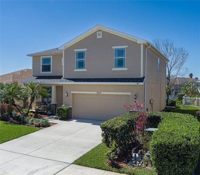 view of front facade with an attached garage, concrete driveway, roof with shingles, and fence