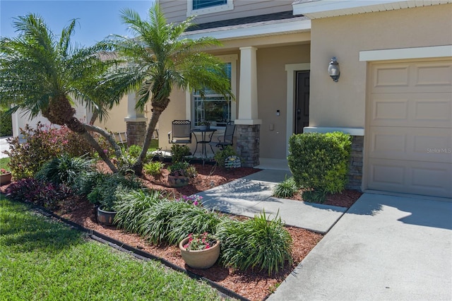 entrance to property with a garage, stone siding, a porch, and stucco siding