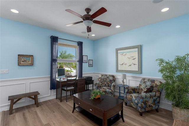 living area featuring light wood-style flooring, recessed lighting, a ceiling fan, and a wainscoted wall